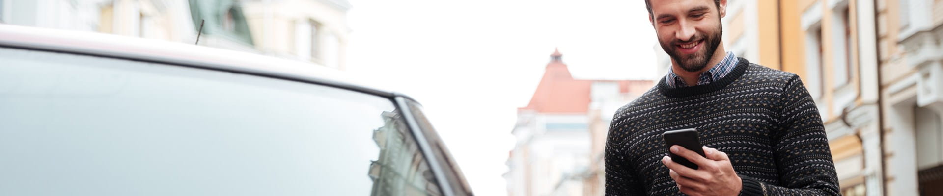 Man is gelukkig wanneer hij op zijn gsm de dekkingen van de BA Autoverzekering van AXA nakijkt