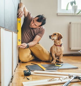 Homme qui rénove sa maison avec son chien à ses côtés