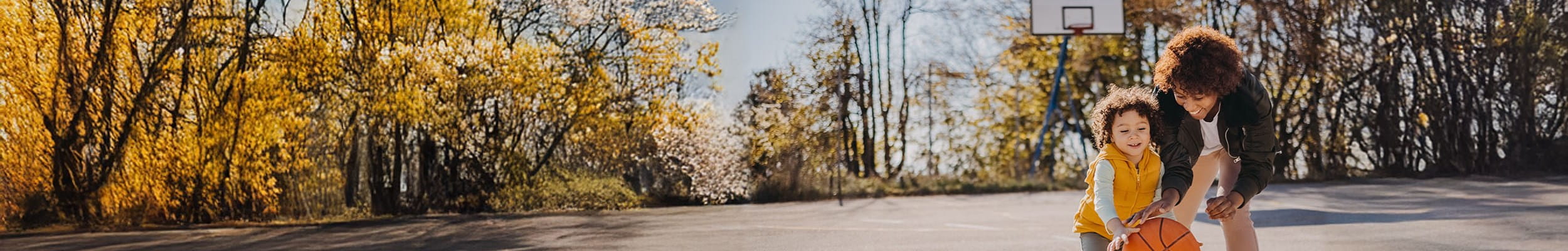 Moeder en kind spelen basketbal, gedekt door de Familiale verzekering van AXA in geval van schade veroorzaakt aan anderen.