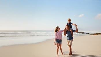 Parents et leurs enfants profitent pleinement d'une promenade sur la plage grâce à l'assurance voyage AXA.