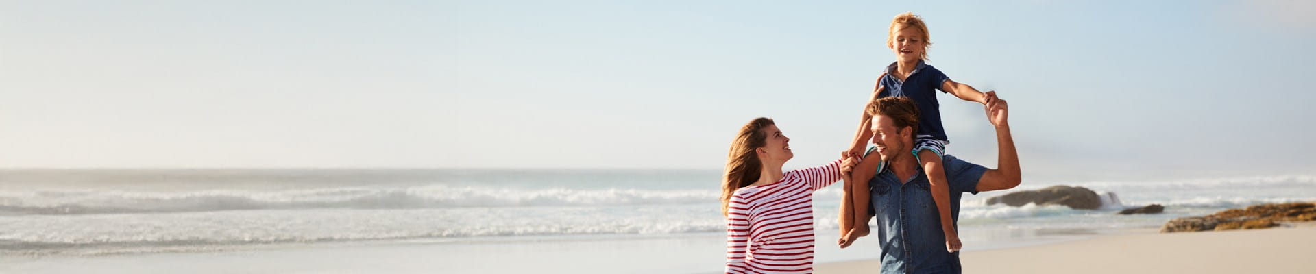 Parents et leurs enfants profitent pleinement d'une promenade sur la plage grâce à l'assurance voyage AXA.
