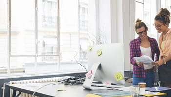 Twee vrouwen in een kantoor die de spaarformules voor een aanvullend pensioen voor starters bekijken