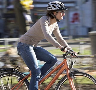 Vrouw fietst veilig in de stad met een goede fietsuitrusting.
