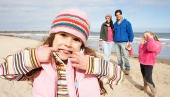 Une famille avec deux enfants profite d'une promenade sur la plage en toute sérénité grâce à la protection offerte par leurs assurances familiale et accidents vie privée.
