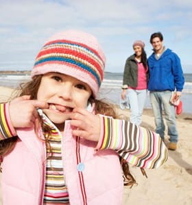 Une famille avec deux enfants profite d'une promenade sur la plage en toute sérénité grâce à la protection offerte par leurs assurances familiale et accidents vie privée.