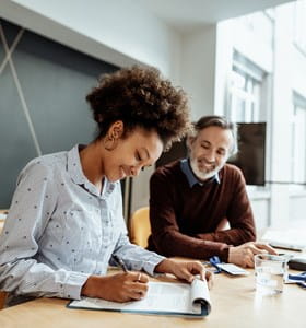 Une femme accompagnée de son intermédiaire en assurances pour changer de formule d’assurance concernant l’ajout ou la suppression d’une garantie à son contrat d’assurance