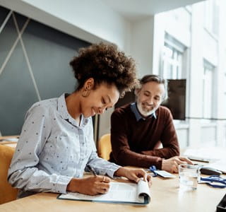 Une femme accompagnée de son intermédiaire en assurances pour changer de formule d’assurance concernant l’ajout ou la suppression d’une garantie à son contrat d’assurance