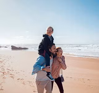 Jeune famille profitant d’une promenade sur la plage. Grâce à une assurance investissement, elle construit son avenir financier.
