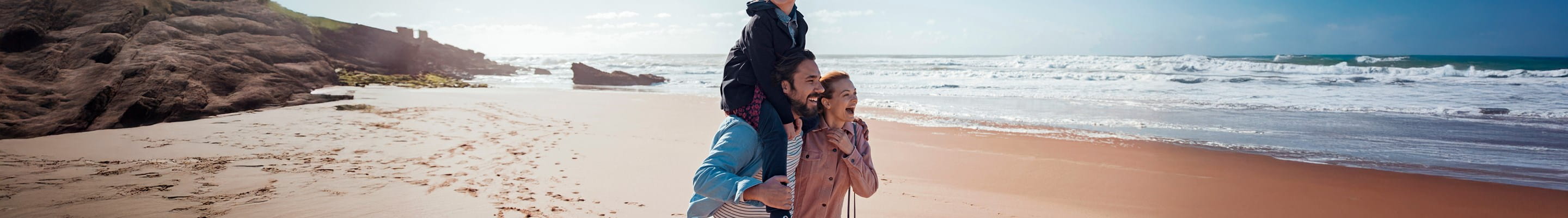 Jeune famille profitant d’une promenade sur la plage. Grâce à une assurance investissement, elle construit son avenir financier.