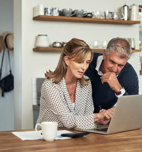 Couple analyse sur son portable les possibilités offertes par une assurance-vie dans le cadre de la taxation sur les plus-values.