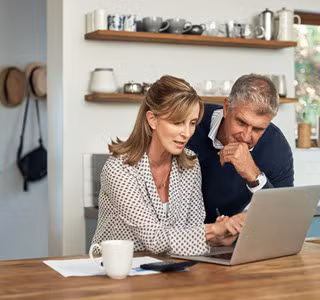 Couple analyse sur son portable les possibilités offertes par une assurance-vie dans le cadre de la taxation sur les plus-values.