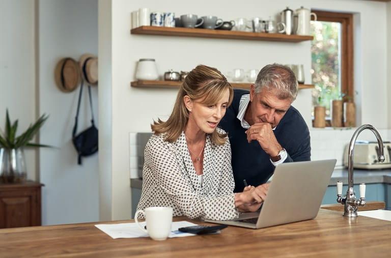 Couple analyse sur son portable les possibilités offertes par une assurance-vie dans le cadre de la taxation sur les plus-values.
