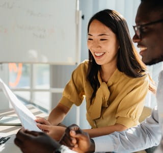 Twee collega’s bekijken samen een document op een laptop, om bij arbeidsongeschiktheid van de bedrijfsleider de continuïteit van de activiteit te garanderen.