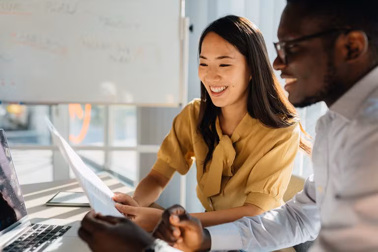 Twee collega’s bekijken samen een document op een laptop, om bij arbeidsongeschiktheid van de bedrijfsleider de continuïteit van de activiteit te garanderen.