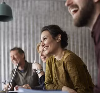 Des collègues enthousiastes et créatifs, assis autour d'une table de réunion, regardant au loin dans une salle de conseil.