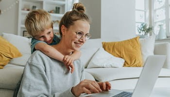 Een moeder wint informatie in over ongevallen tijdens de werkuren, terwijl haar zoontje over haar schouder meekijkt.