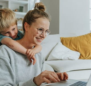 Een moeder wint informatie in over ongevallen tijdens de werkuren, terwijl haar zoontje over haar schouder meekijkt.