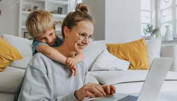Een moeder wint informatie in over ongevallen tijdens de werkuren, terwijl haar zoontje over haar schouder meekijkt.