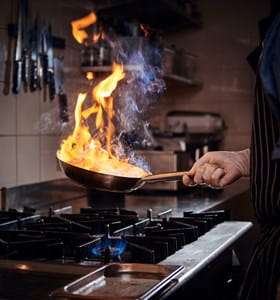 Poêle en feu dans une cuisine, qui crée un risque d’incendie domestique.