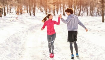 Twee jonge mensen genieten van de sneeuw in de winter en zorgen zo voor een gezonde levensstijl.