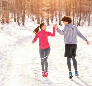 Twee jonge mensen genieten van de sneeuw in de winter en zorgen zo voor een gezonde levensstijl.
