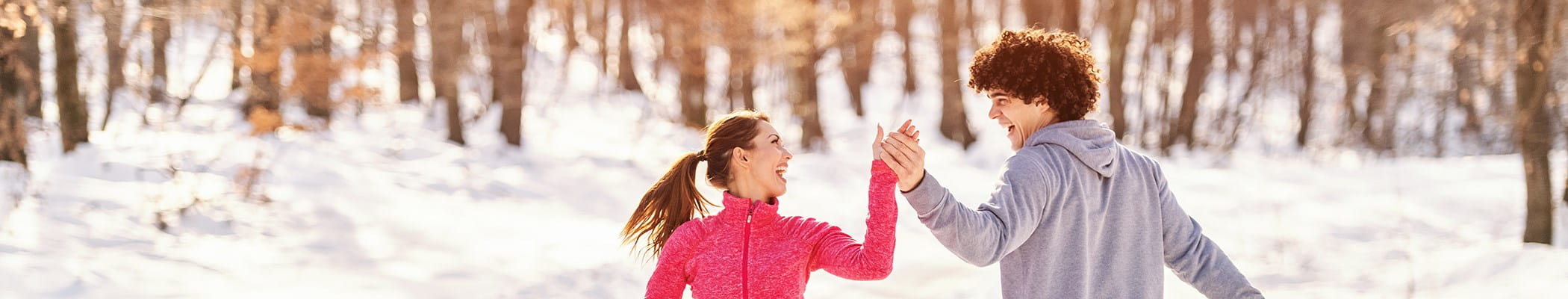 Twee jonge mensen genieten van de sneeuw in de winter en zorgen zo voor een gezonde levensstijl.