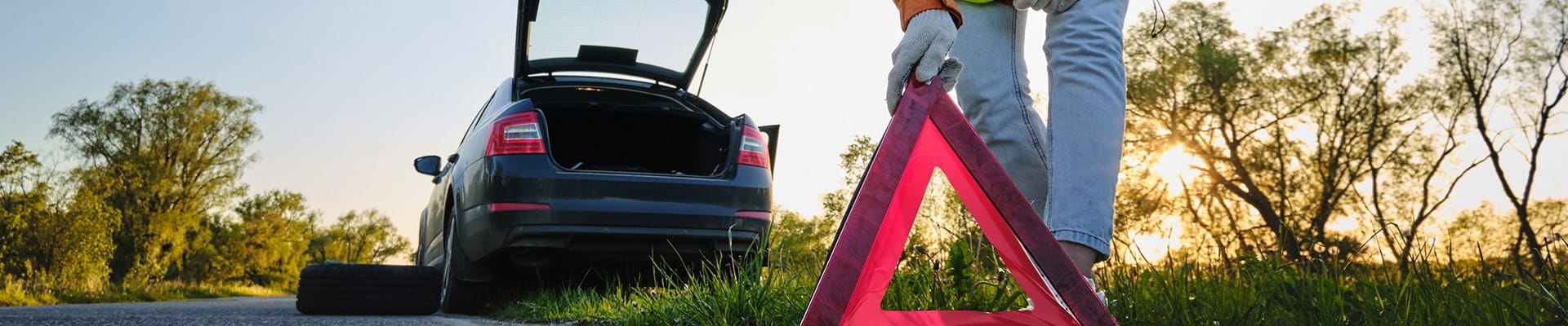 Femme change une roue de voiture après un accident et place le triangle de signalisation.