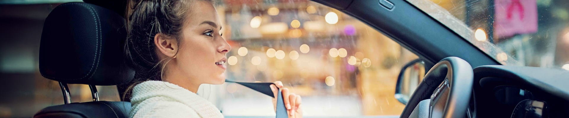 Vrouw gaat zo dadelijk vertrekken in de lage-emissiezone en doet haar gordel om.