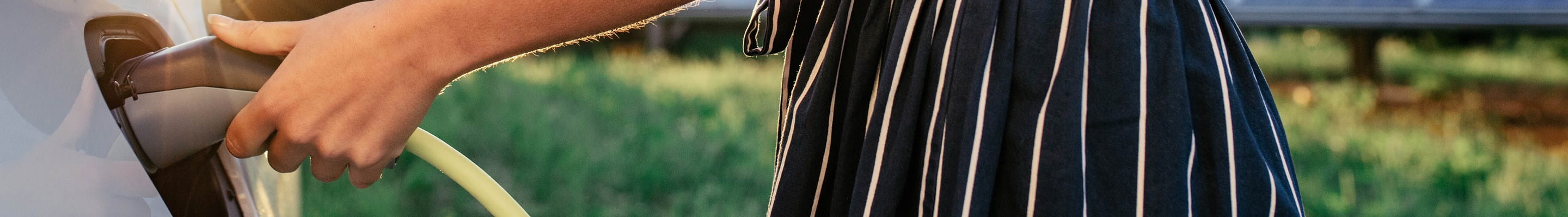 Femme rechargeant sa voiture électrique un jour d'été.