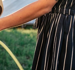 Vrouw die haar elektrische auto oplaadt op een zomerse dag.