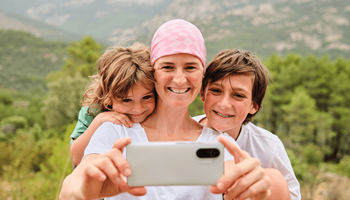 Une femme atteinte de cancer utilise un smartphone pour prendre un selfie avec son fils et sa fille.