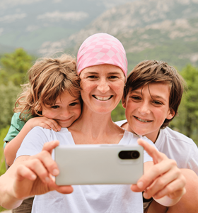 Une femme atteinte de cancer utilise un smartphone pour prendre un selfie avec son fils et sa fille.