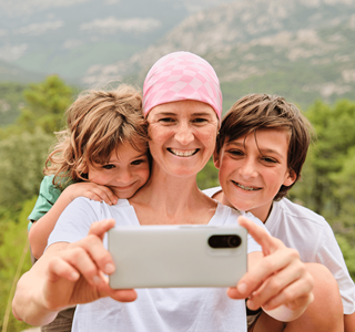 Une femme atteinte de cancer utilise un smartphone pour prendre un selfie avec son fils et sa fille.