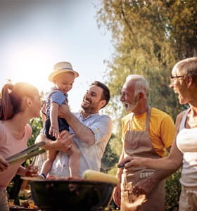 Une famille avec grands-parents, enfants et petits-enfants autour d'un barbecue convivial