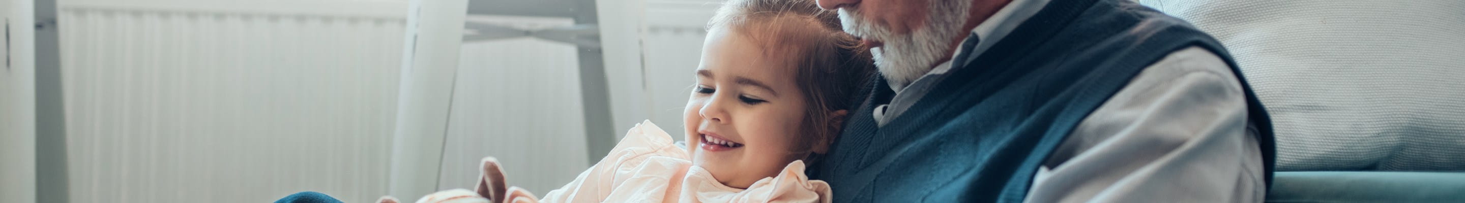 Grand-père qui a désigné sa petite-fille comme bénéficiaire dans un contrat d'assurance-vie et qui joue avec elle et sa peluche dans le séjour.