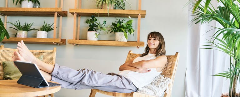 Vrouw zit ontspannen in haar huis, gerustgesteld door haar woonverzekering.