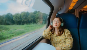 Vrouw reist met de trein terug naar huis en luistert naar muziek.