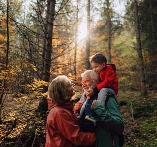 Grootvader, dochter en kleindochter wandelen in het bos en voeren een gesprek over de levensverzekering als successieplanningsinstrument.