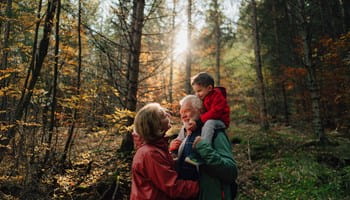 Grootvader, dochter en kleindochter wandelen in het bos en voeren een gesprek over de levensverzekering als successieplanningsinstrument.