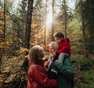 Grootvader, dochter en kleindochter wandelen in het bos en voeren een gesprek over de levensverzekering als successieplanningsinstrument.