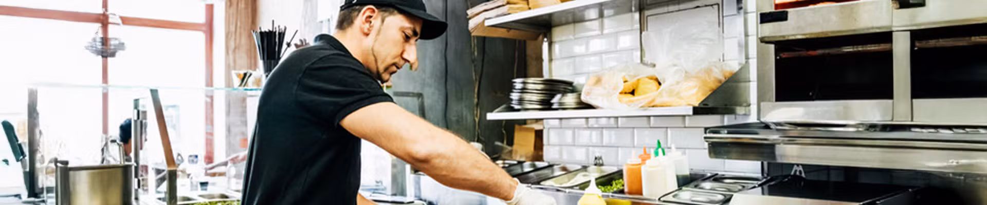Un membre du personnel de l'horeca prépare et sert des plats selon les directives d'AFSCA et HACCP.