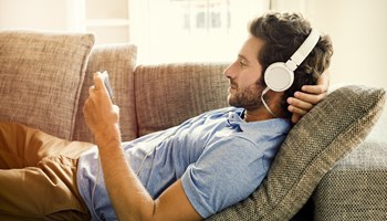 Jeune homme souscrivant son épargne pension sur son téléphone en écoutant de la musique