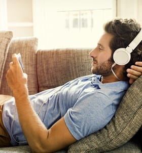 Jeune homme souscrivant son épargne pension sur son téléphone en écoutant de la musique