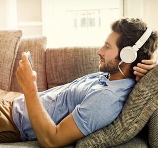 Jeune homme souscrivant son épargne pension sur son téléphone en écoutant de la musique