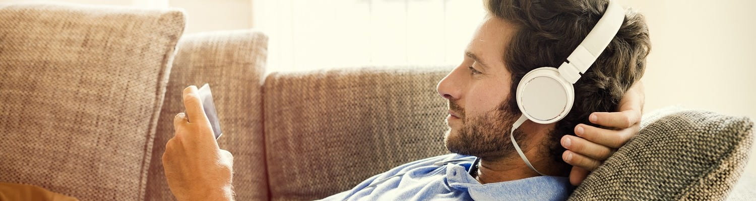 Jeune homme souscrivant son épargne pension sur son téléphone en écoutant de la musique