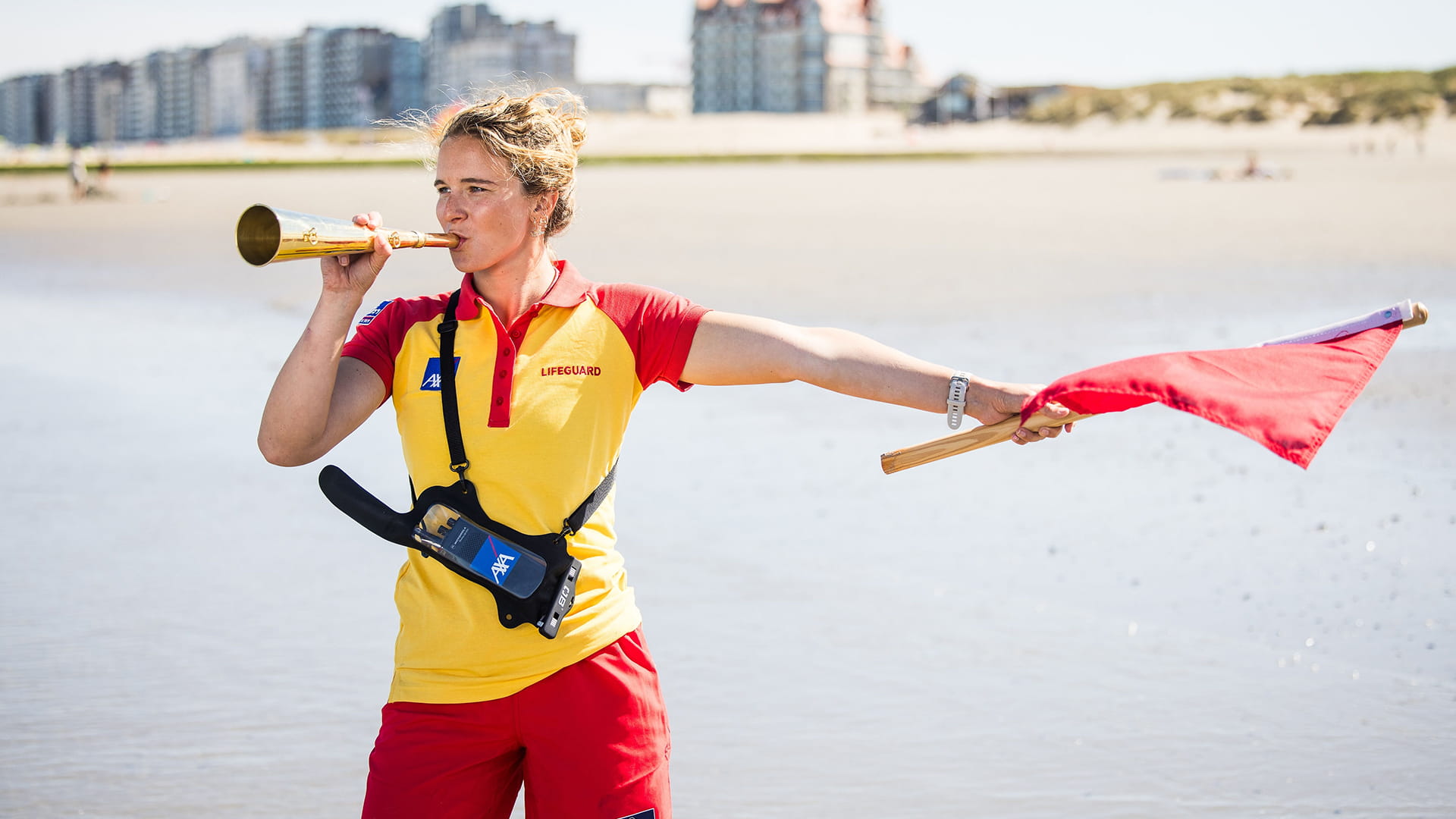 Lifeguard aan de Belgische kust zwaait met de rode vlag om ongevallen te voorkomen.