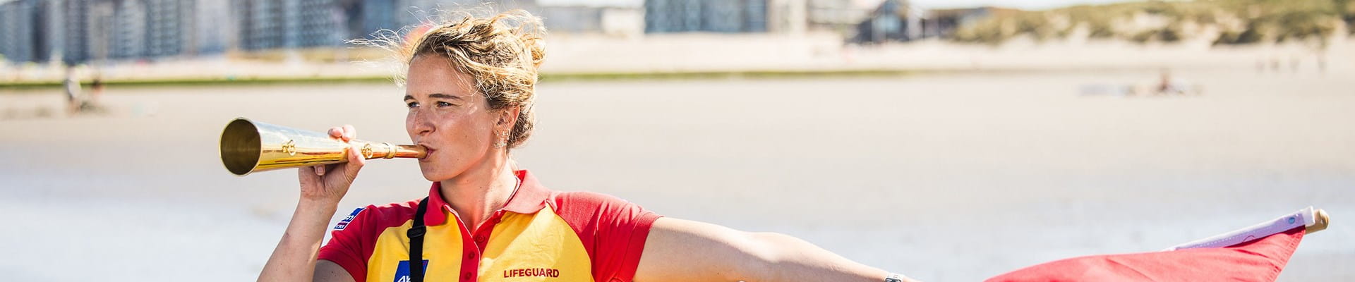 Lifeguard aan de Belgische kust zwaait met de rode vlag om ongevallen te voorkomen.
