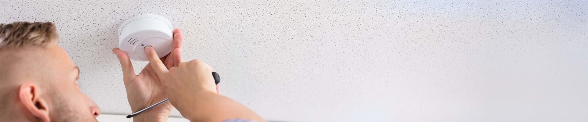 Propriétaire qui vérifie le bon fonctionnement de son détecteur de fumée.