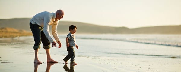 Dankzij een gepaste reisverzekering speelt een man ontspannen met zijn kind op het strand.