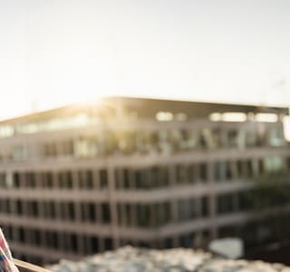 Oudere dame geniet van haar aanvullend pensioen en kijkt naar appartementen vanop haar balkon.